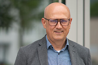 Foto of Alexander Alexander Fillips, Director Enterprise Solutions at MicroNova, bright portrait with dark blue suite and black glasses