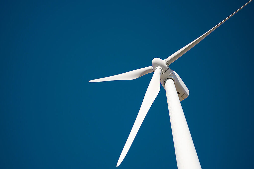 Wind turbine from below in front of a blue sky